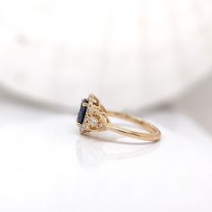 a diamond and blue sapphire ring sitting on top of a white surface