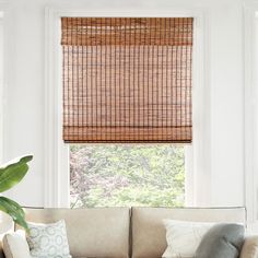 a living room with a couch and window covered in bamboo blinds