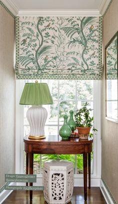 a table with two vases and a lamp on top of it in front of a window