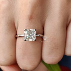 a close up of a person's hand with a diamond ring on their finger