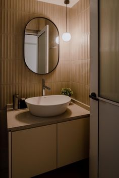 a bathroom sink sitting under a round mirror