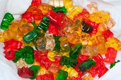 a pile of gummy bears sitting on top of a white cloth covered in candy