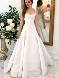 a woman standing in front of a mirror wearing a white wedding dress