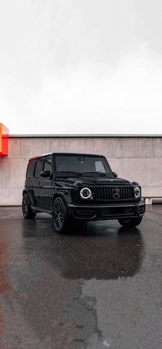 a black mercedes g - class is parked in front of a building with an orange sign