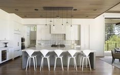 a kitchen with white chairs and an island