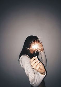 a woman holding a sparkler up to her face