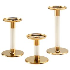 three gold and white candlesticks are shown