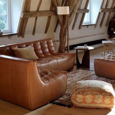 a living room filled with brown leather furniture and wooden beams on the wall behind it