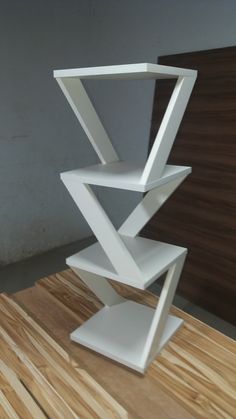 a tall white shelf sitting on top of a wooden table next to a wall and floor