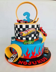 a three tiered cake with hot wheels on top