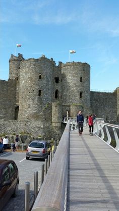 people are walking across a bridge near a castle