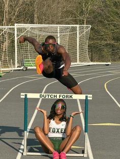 a woman jumping over a hurdle on top of a race track