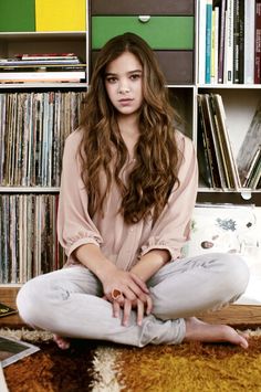 a woman sitting on the floor in front of a bookshelf