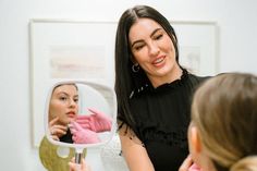 a woman is looking at her reflection in the mirror