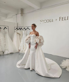 a woman is standing in front of some wedding gowns