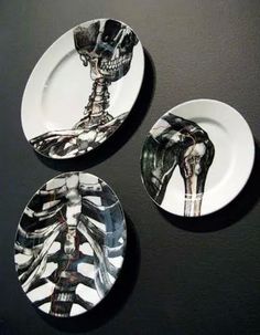 three plates with skeleton designs on them sitting on a black table top next to each other