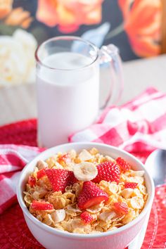 a bowl of oatmeal with strawberries and bananas next to a glass of milk