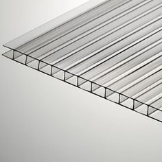 a close up view of the top of a glass shelf against a white wall with black lines