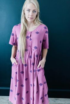 This modest embroidered dress is purple with navy blue embroidery. It has pockets, short sleeves, and is midi length. You can wear it to work in the summer. It also has buttons and is nursing friendly. Shop now! #modest #dresses Navy Blue Embroidery, Nursing Friendly, Blue Embroidery, Sleeves Dress, Office Dresses