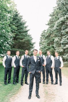 a group of men standing next to each other in front of some green trees and grass