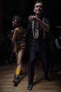 a man and woman dancing on a wooden floor in front of a group of people