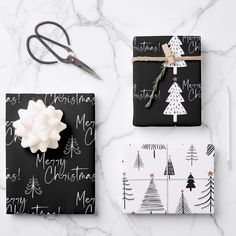 wrapping presents for christmas on a marble countertop with scissors and other holiday gifts wrapped in black paper