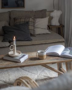 a coffee table with a candle on it in front of a book and magazine sitting on top of it