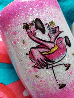 a pink flamingo is painted on the side of a cup with gold flakes