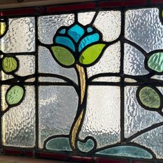 a close up of a stained glass window with flowers on it's side and green leaves