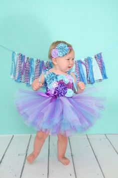 *Please check turn around times. All items are made to order* This listing is for an Under the Sea Birthday Tutu Dress that is simply stunning. Made with purple, lavender, and turquoise tulle. Bodice is adorned with multiple styles of different colored flowers to match. Comes with turquoise satin straps that ties over the shoulders in a pretty bow. Headband and banner is not included but can be purchased from my shop. Link to Banner - https://www.etsy.com/listing/232018738/purple-and-blue-fabric Playful Purple Princess Dress For Summer, Playful Purple Tulle Tutu Dress, Playful Purple Tutu Dress For Birthday, Whimsical Summer Tutu Dress For Cake Smash, Purple Summer Birthday Dress, Blue Tulle Dress For First Birthday, Purple Sleeveless Dress For Birthday, Purple Sleeveless Tutu Dress For Birthdays, Purple Sleeveless Tutu Dress For Birthday