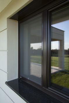 an open window sitting on the side of a white wall next to a grass field