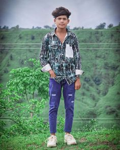 a young man standing on top of a lush green hillside