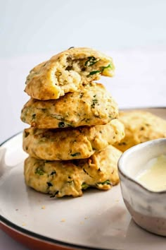 three biscuits stacked on top of each other next to a bowl of butter and sauce