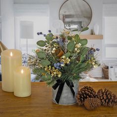 a vase filled with flowers sitting on top of a wooden table next to two candles