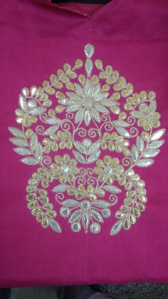 a pink shirt with gold embroidery on it