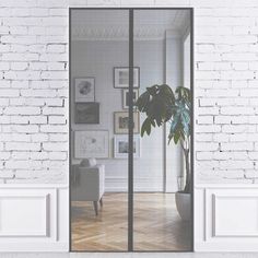 an open glass door leading to a living room with white brick walls and wooden floors