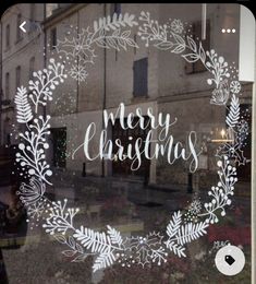 a window with the words merry christmas written in white on it's glass and surrounded by snowflakes