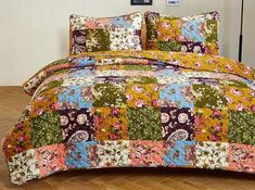 a bed covered in a colorful patchwork comforter and pillow case with matching pillows