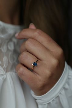 a woman wearing a gold ring with a blue stone