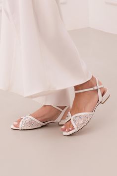 Step into the spotlight with our Kore wedding flat sandals, the epitome of luxury and elegance. These stunning white bridal flats feature a flattering butterfly-shaped toe strap, handcrafted from supple leather and structured mesh, adorned with exquisite hand-embroidered lace. Tiny transparent sequins and blue beads lend a subtle sparkle, offering a perfect "something blue" for your big day. Designed for both style and comfort, the Kore white bridal flats are richly padded to cushion every step, Bridal Shoes Flats Sandals, White Wedding Shoes Flats, Bridal Sandal, Something Blue For Bride, Flat Sandals Wedding, Bridal Flats, Bridal Shoes Flats, Wedding Shoes Flats, Wedding Flats