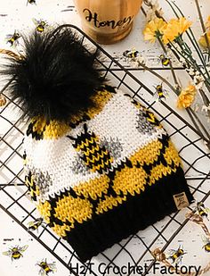 a knitted hat sitting on top of a wire rack next to flowers and a jar