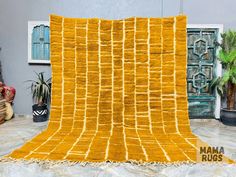 a large yellow blanket sitting on top of a white table next to potted plants