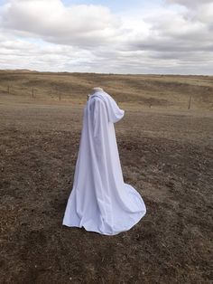 a person in a white robe standing in a field