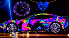 a colorful car is on display in front of a heart - shaped clock and neon lights