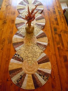 a wooden table topped with two circular rugs and a vase filled with red flowers