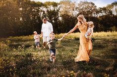 a woman and two children are holding hands as they walk through the grass with their parents