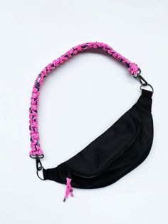 a black fanny bag with pink braiding on the side and a pink ribbon around it