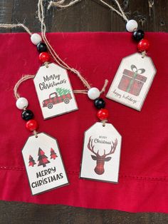 three christmas tags hanging on a red cloth