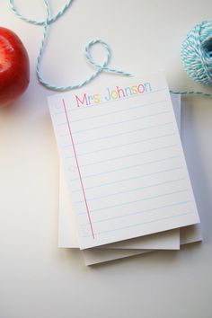 notepads with the name mrs johnson on them next to an apple and yarn