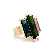 This 14 karat yellow gold cocktail ring is a bold statement of color, featuring a striking 2.68 carat emerald cut green tourmaline as its centerpiece. Flanked by two vibrant accent stones—a 1.65 carat blue tourmaline and a pink tourmaline—this ring plays with color in a way that’s both eye-catching and refined. The bar-set stones create a dynamic look that balances the rich hues of green, blue, and pink, making this piece a standout for any occasion. Whether it’s a night out or a day when you si Engagement Ring Style Guide, Ring Style Guide, Jewelry Style Guide, Yellow Gold Cocktail Ring, Wedding Band Styles, Platinum Rose Gold, Sapphire Solitaire, Gold Cocktail Ring, Tourmaline Jewelry